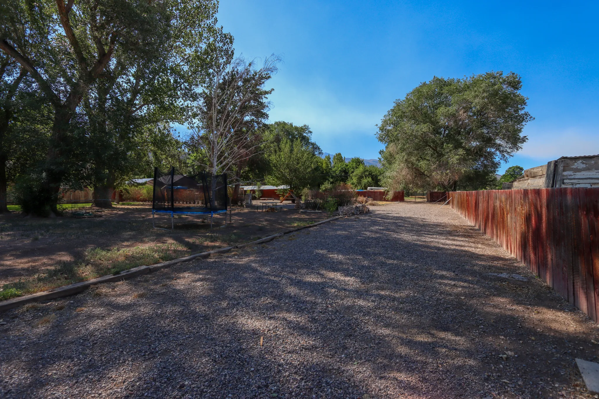 Gravel drive with a reddish-brown wooden fence