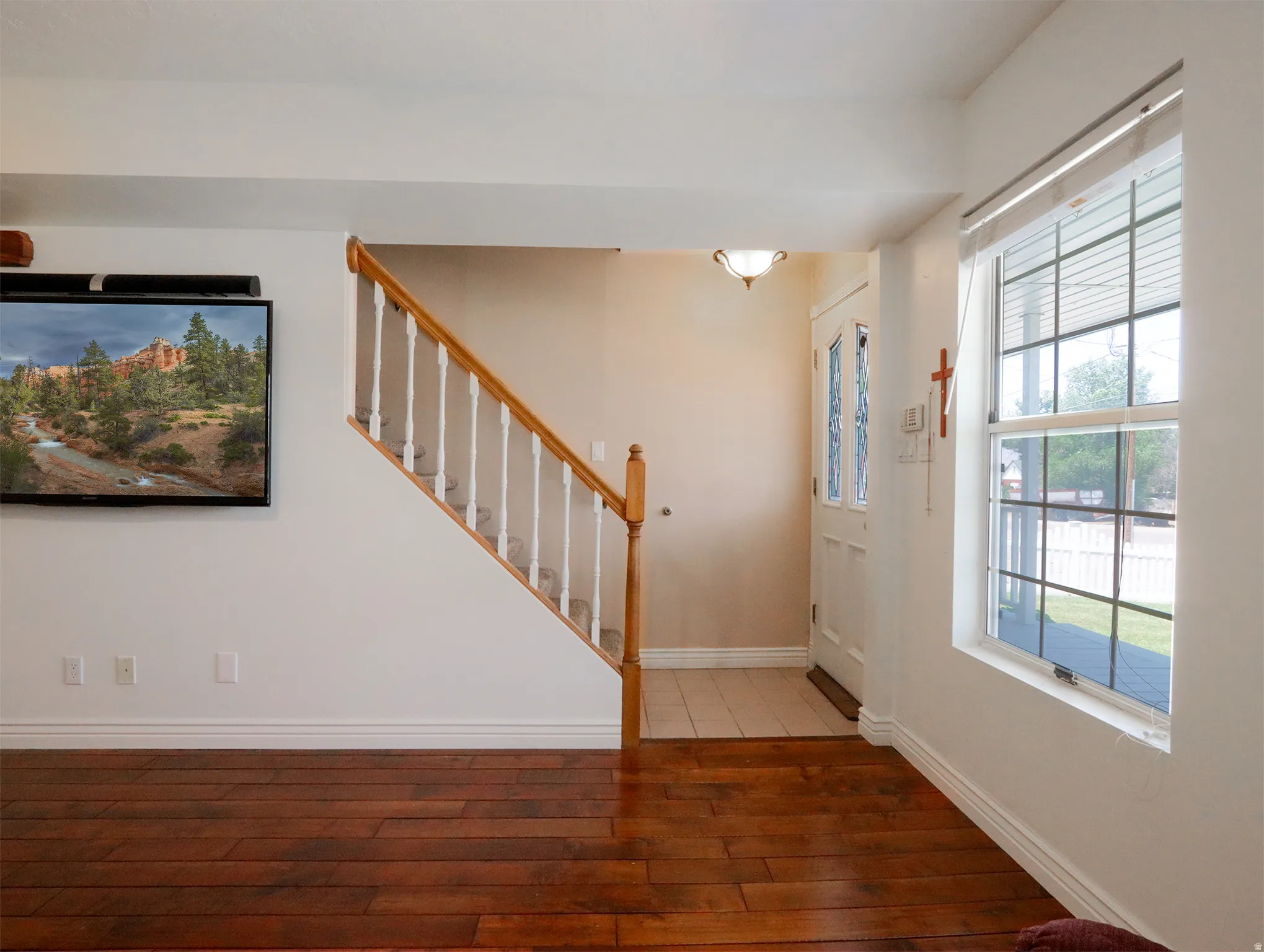Hardwood-finish flooring extending into the living area, featuring a staircase with wood handrails and white balusters