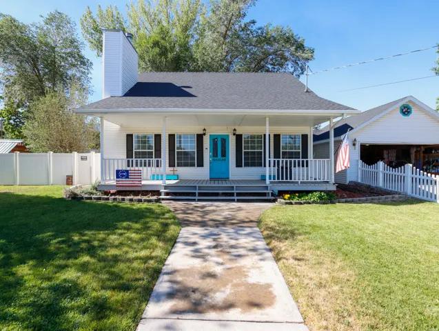 White siding residence featuring a covered front porch, black window shutters, and a vibrant blue entry door