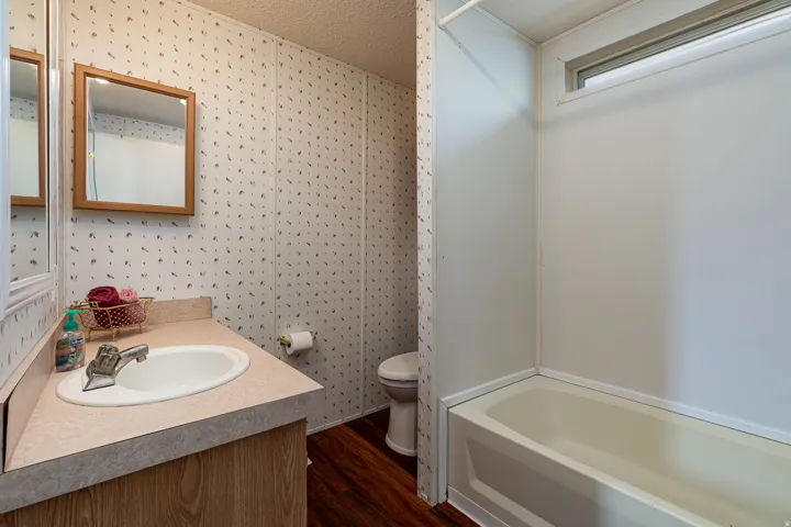 Bathroom featuring a single vanity with integrated sink, wood-finish cabinetry, and a framed mirror