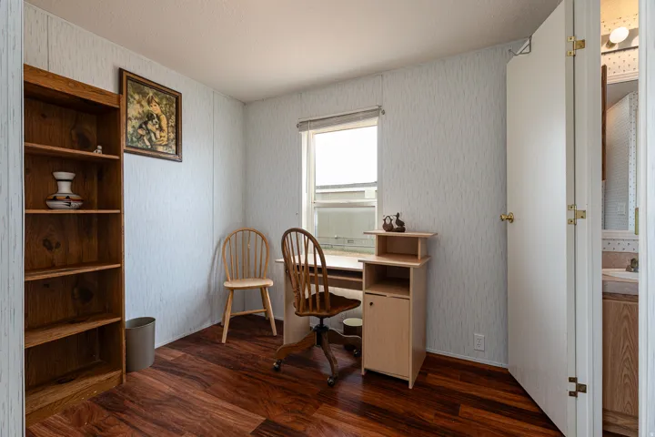 Room featuring wood-finish flooring, a single window, and light-colored textured wall panels
