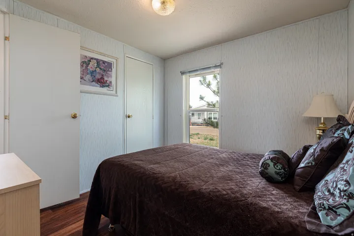 Bedroom featuring wood-finish flooring, textured wall panels, and a ceiling-mounted light fixture