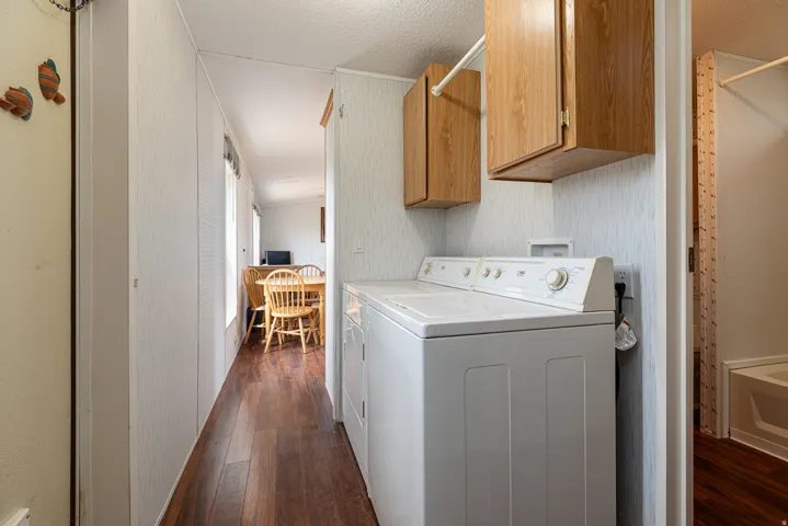Dedicated laundry area featuring overhead cabinetry, a clothing rod, and wood-finish flooring