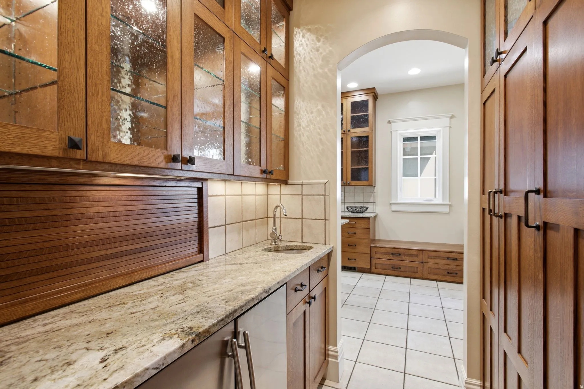 Built-in cabinetry featuring glass-front uppers and a roll-top appliance garage