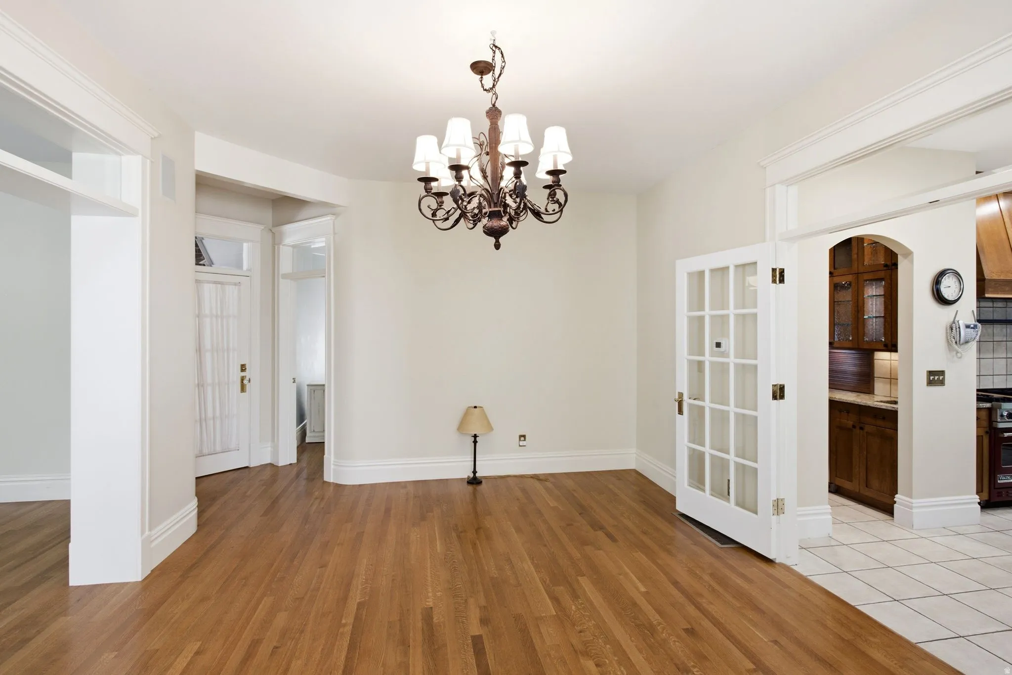 Spacious room featuring wood flooring, a wrought iron chandelier, and white trim