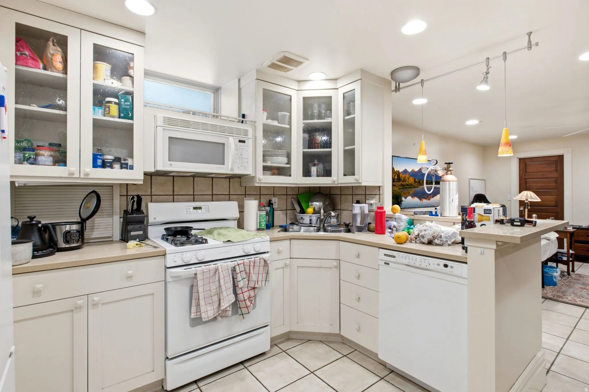 Kitchen featuring white cabinetry, tile flooring, a built-in microwave, an integrated dishwasher, and a breakfast bar