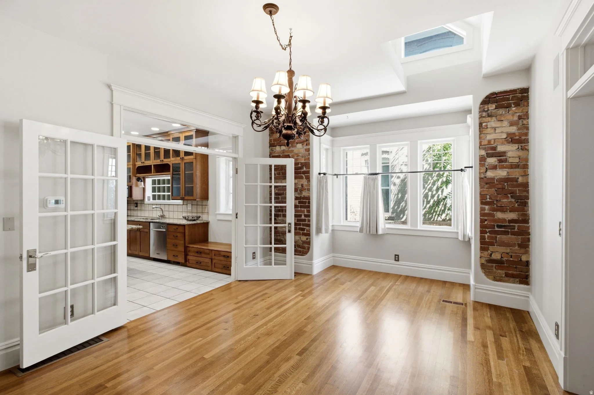 Hardwood flooring extending throughout the space, complemented by a skylight and a bay window