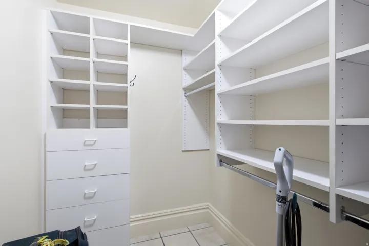 Custom closet system featuring white shelving, multiple hanging rods, and built-in drawers