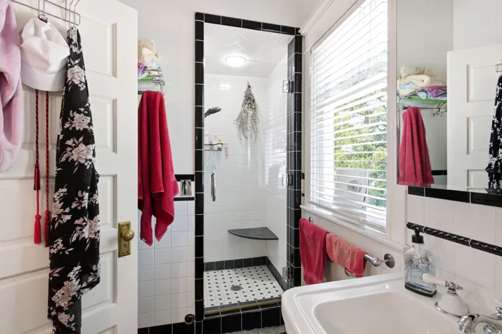 Tiled shower enclosure featuring a black border, glass door, and built-in corner bench