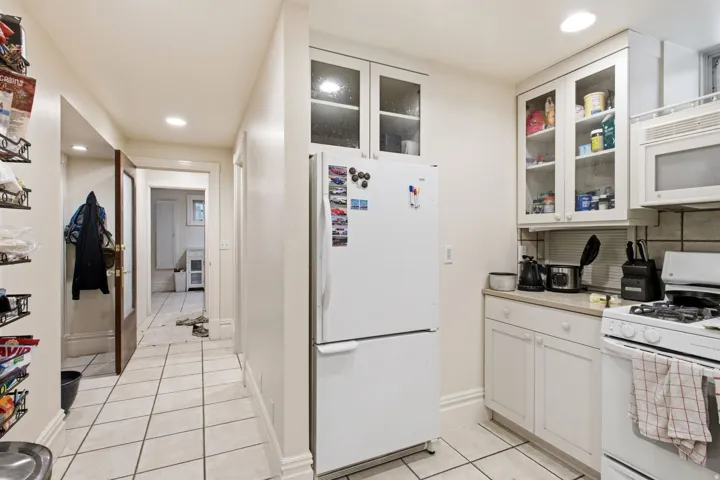 Kitchen featuring white cabinetry, white appliances, and tiled flooring