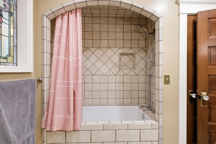 Tile-surround bathtub featuring an arched entry and built-in shower niche