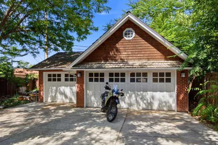 Detached two-car garage featuring white panel doors with upper window inserts