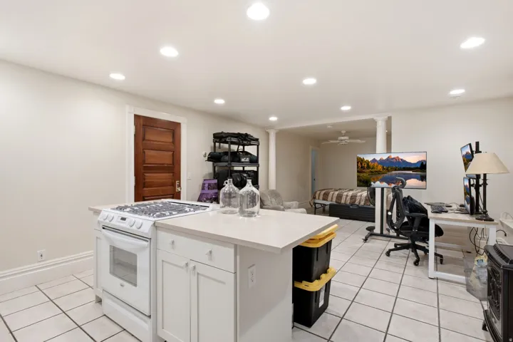Functional kitchen island featuring a gas range and white cabinetry