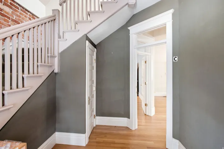 Staircase with white balusters and exposed brick accents
