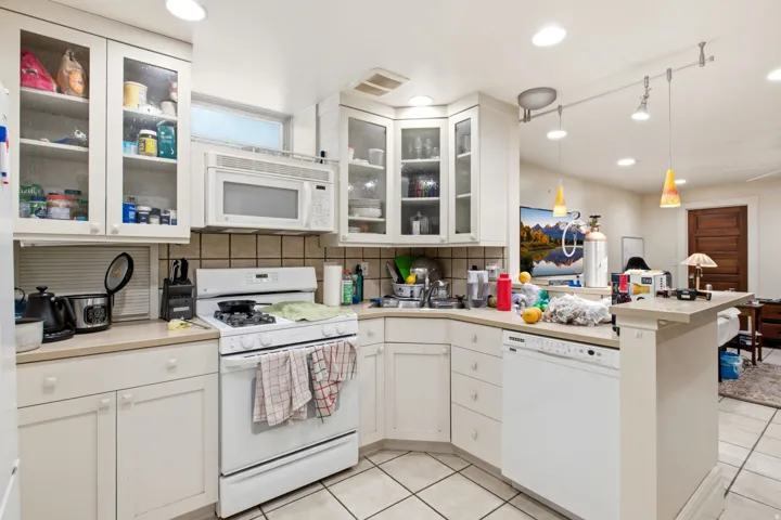 Kitchen featuring white cabinetry, tile flooring, a built-in microwave, an integrated dishwasher, and a breakfast bar