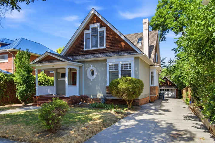 Craftsman-style home featuring a covered front porch with white columns, a shingle gable, and stucco siding