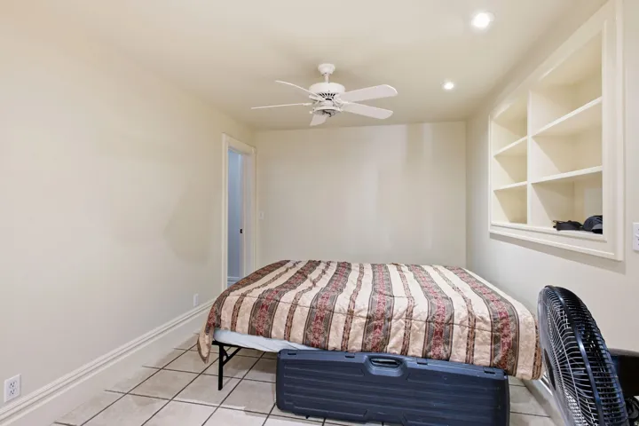 Room featuring tiled flooring, crown molding, built-in shelving, a ceiling fan, and recessed lighting
