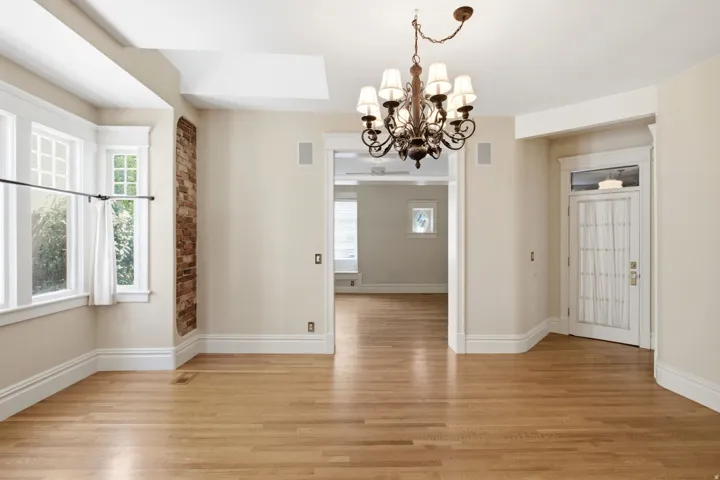 Spacious interior featuring wood-finish flooring, a decorative chandelier, and a bay window