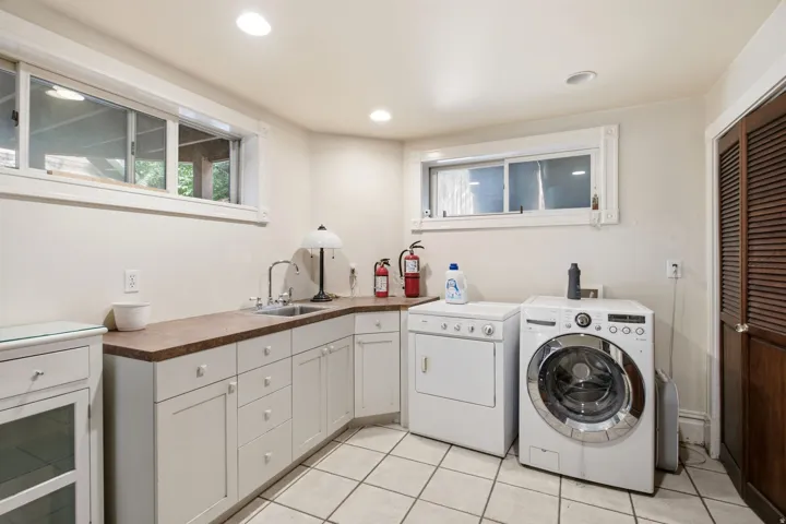 Laundry area featuring white cabinetry, a built-in sink, and a brown countertop