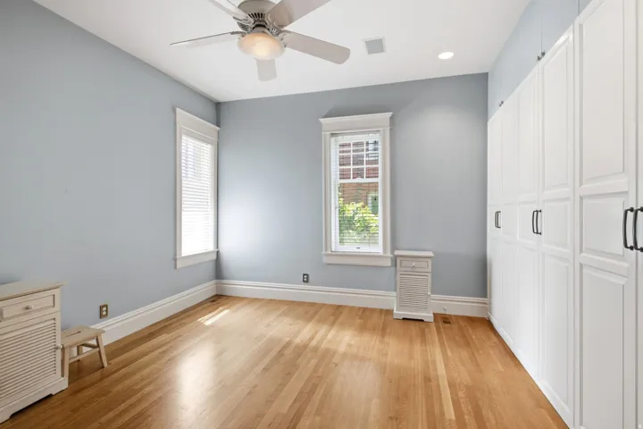 Room featuring extensive built-in white cabinetry with dark pulls, wood-finish flooring, and light blue wall tones