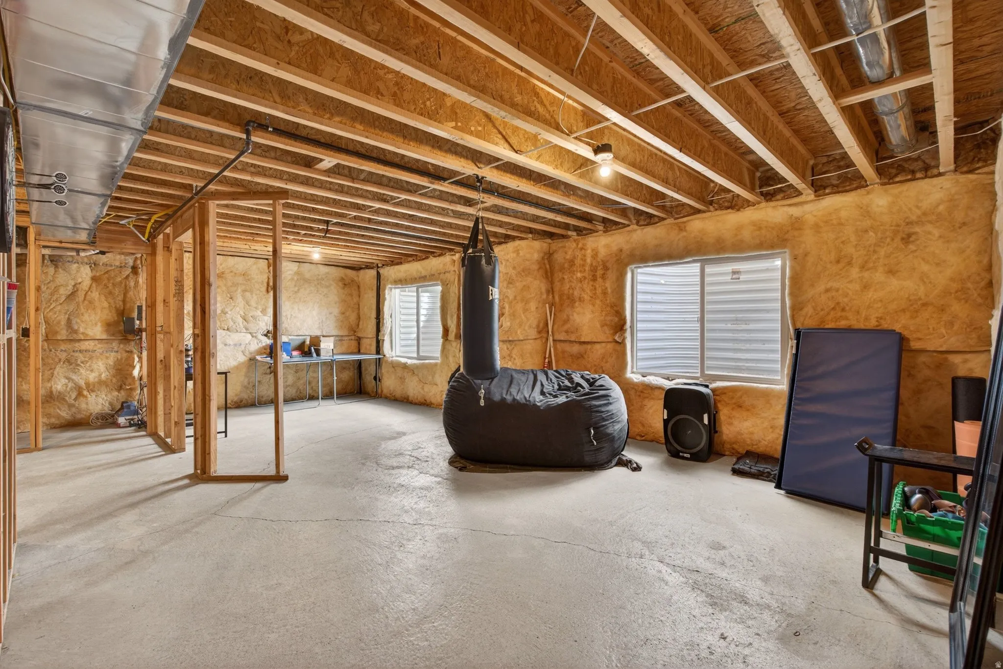 Unfinished basement space featuring exposed wood joists and concrete flooring