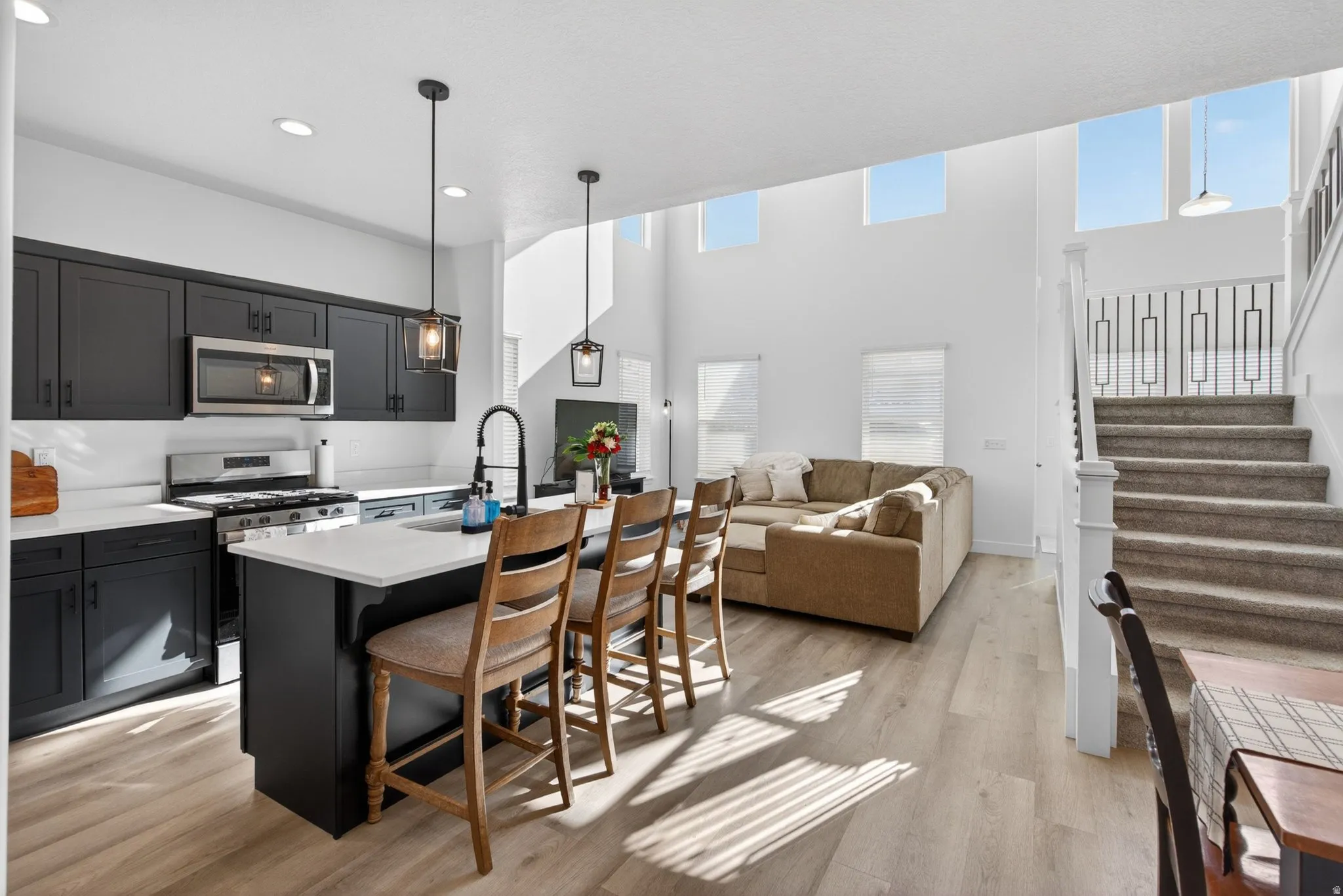 Open-concept living area featuring a kitchen island with seating, stainless steel appliances, and wood-finish flooring