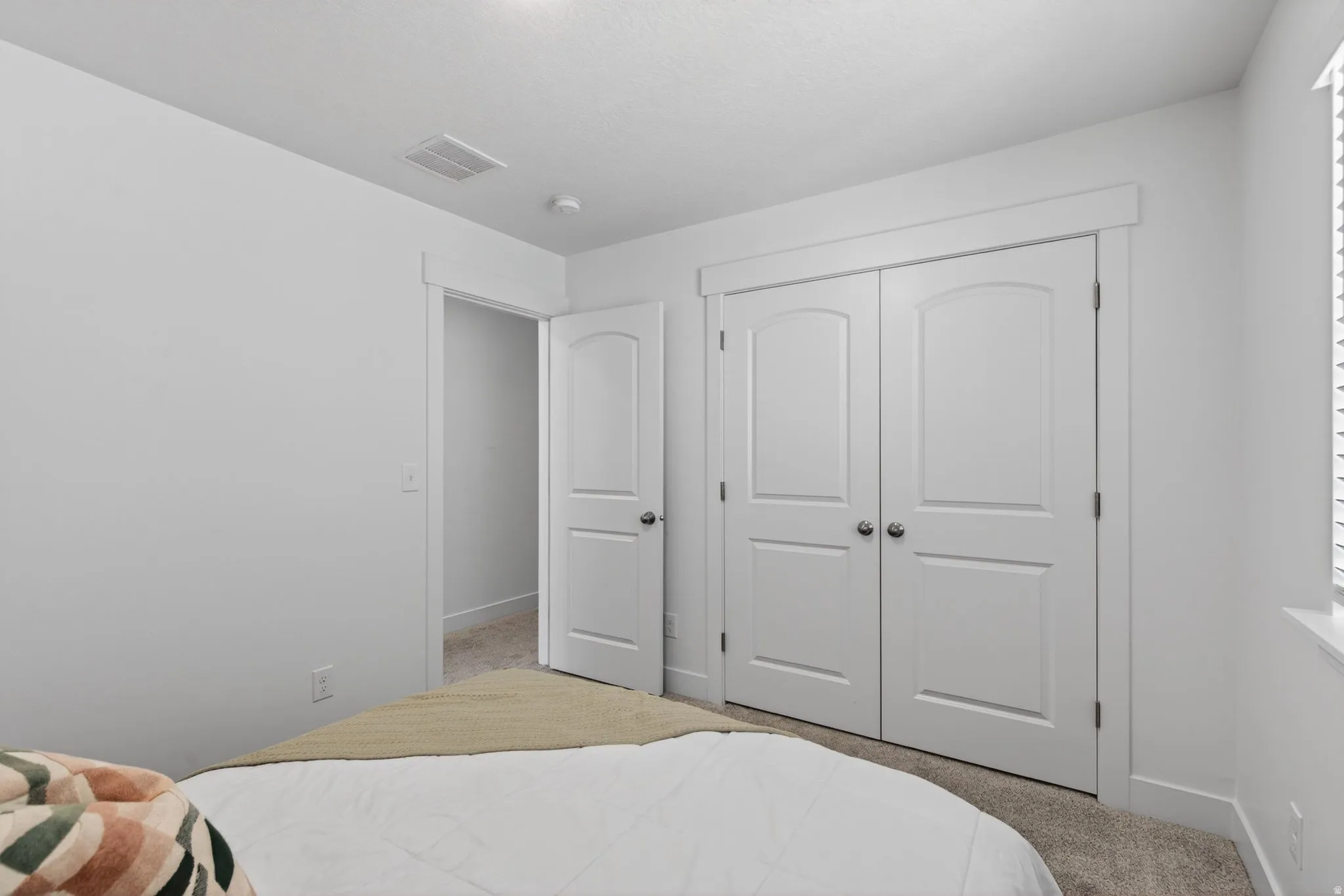 Bedroom featuring light neutral carpeting, white walls, and bright white trim