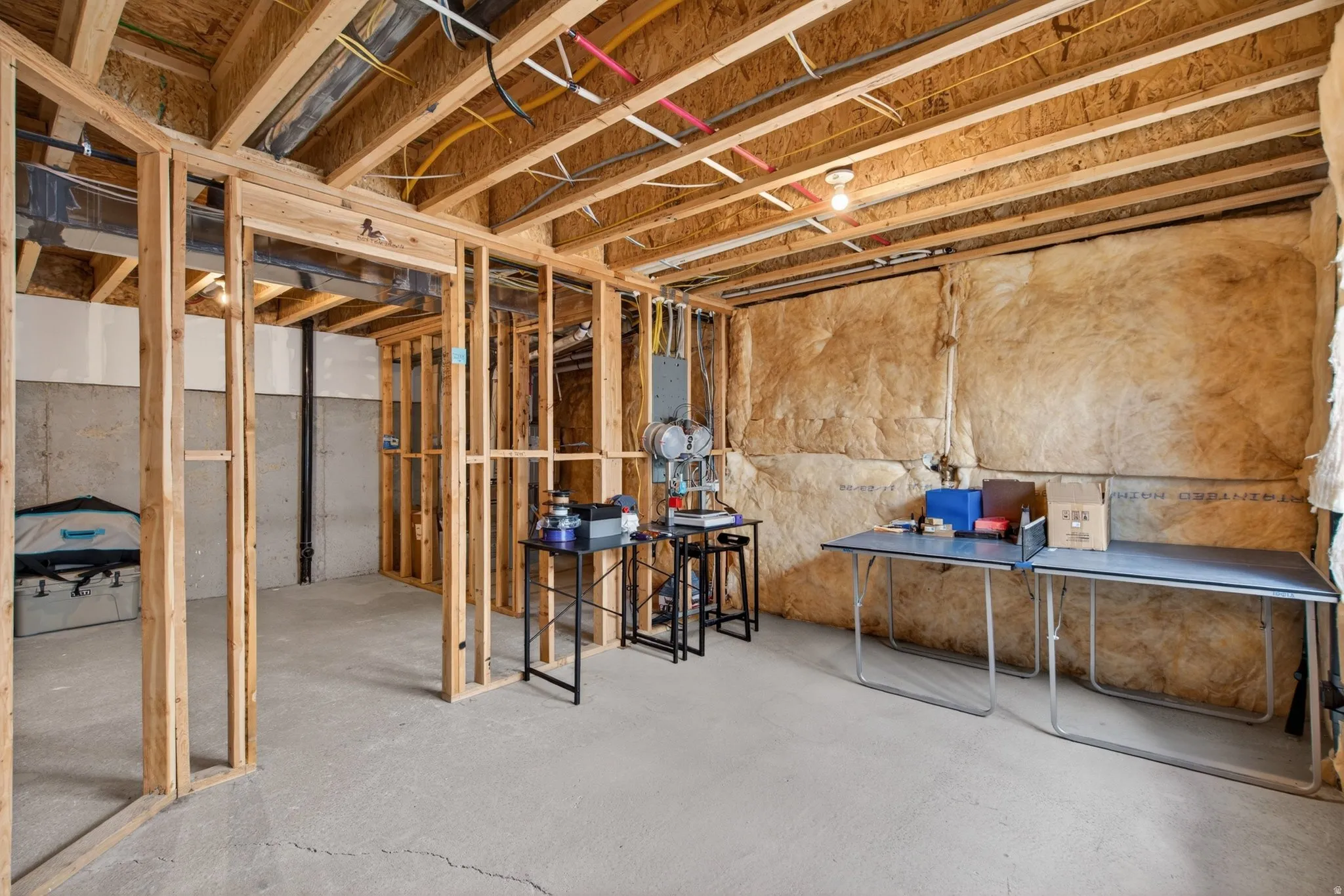 Unfinished basement featuring wood framing, concrete flooring, exposed ceiling joists, and insulated exterior walls