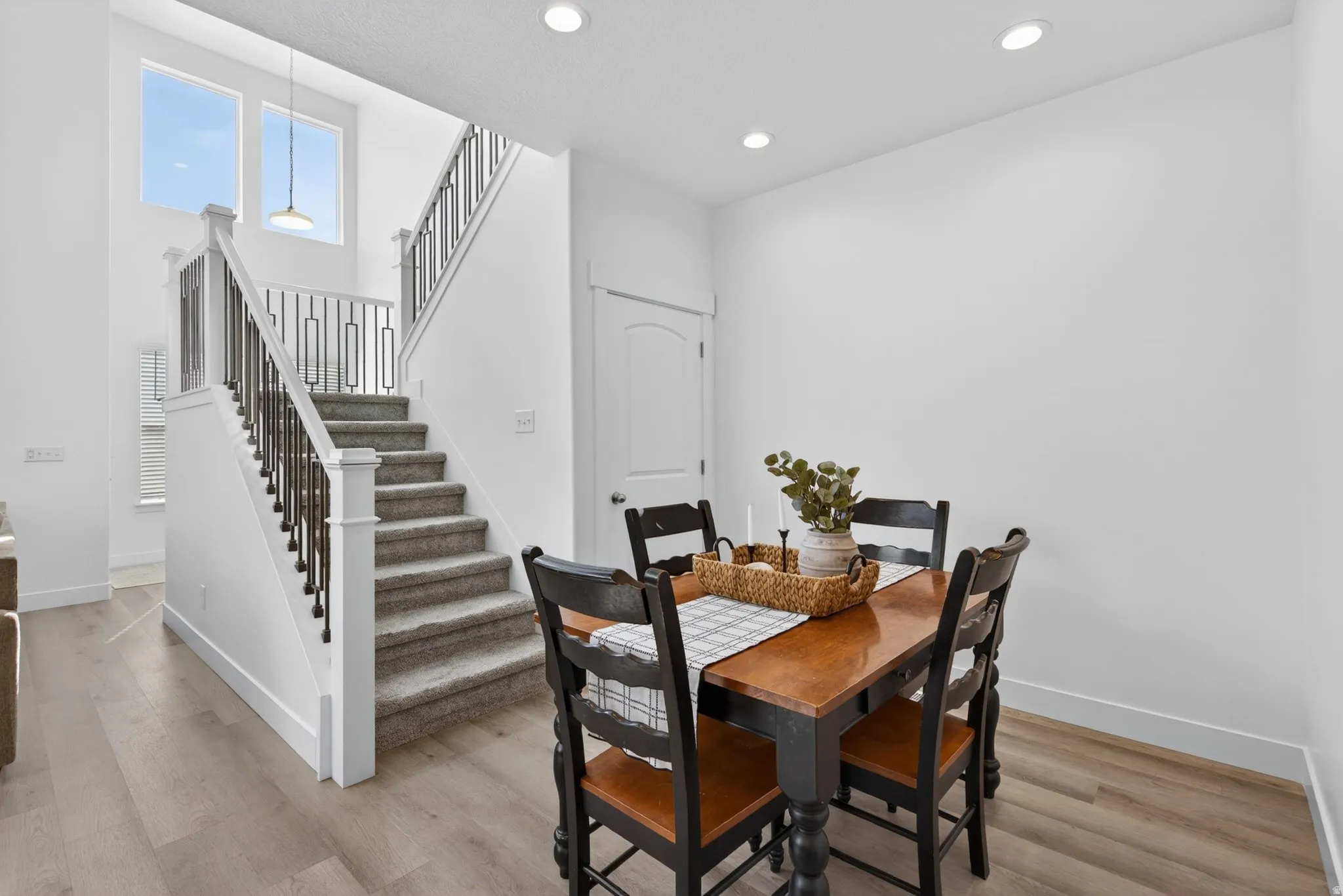 Two-story entryway featuring a carpeted staircase with decorative metal balusters, high ceilings, recessed lighting, and wood-finish flooring