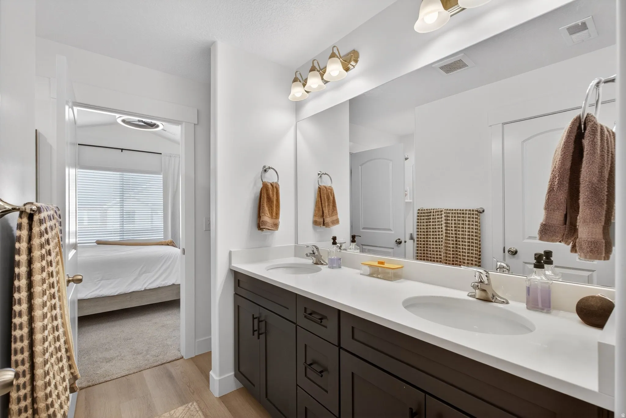 Double vanity with dark wood-finish cabinetry, white countertops, and integrated sinks