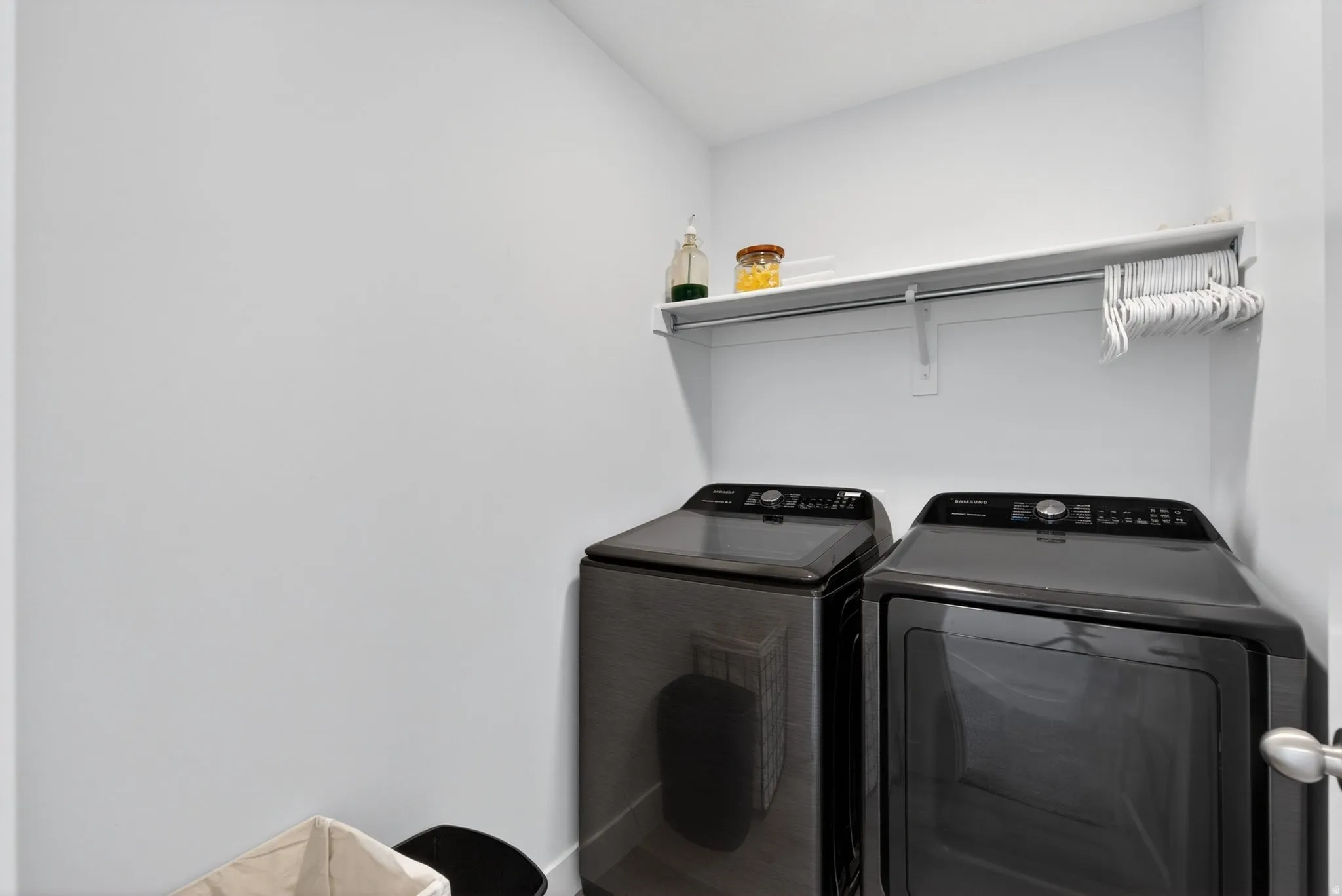 Dedicated laundry area featuring a white wall shelf, metal hanging rod, and light-colored walls