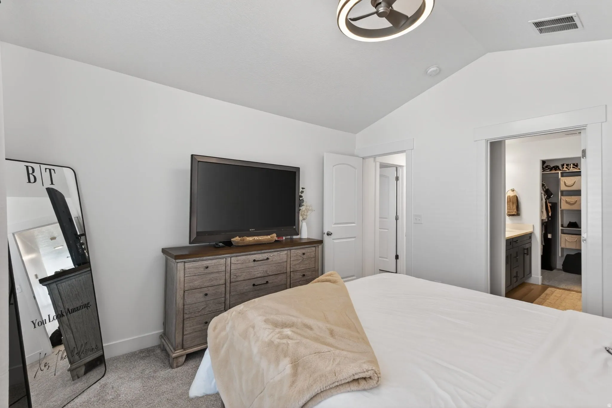 Vaulted ceiling with a contemporary ceiling fan, white paneled doors, and plush carpet flooring