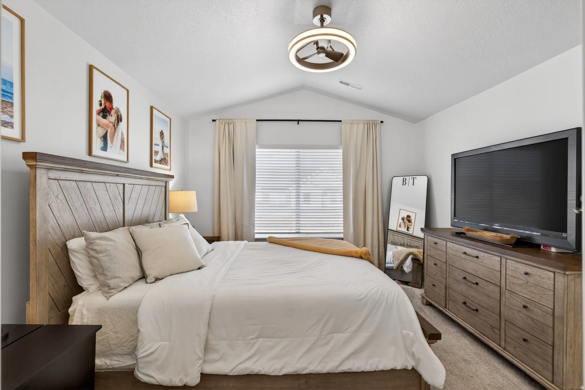 Vaulted ceiling bedroom featuring a window with blinds and drapes, a modern ceiling fan, and carpet flooring