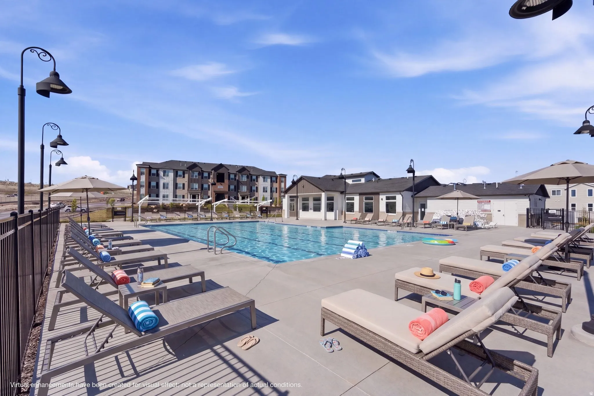 Outdoor swimming pool with integrated lap lanes, surrounded by a concrete deck with multiple lounge chairs and shade umbrellas