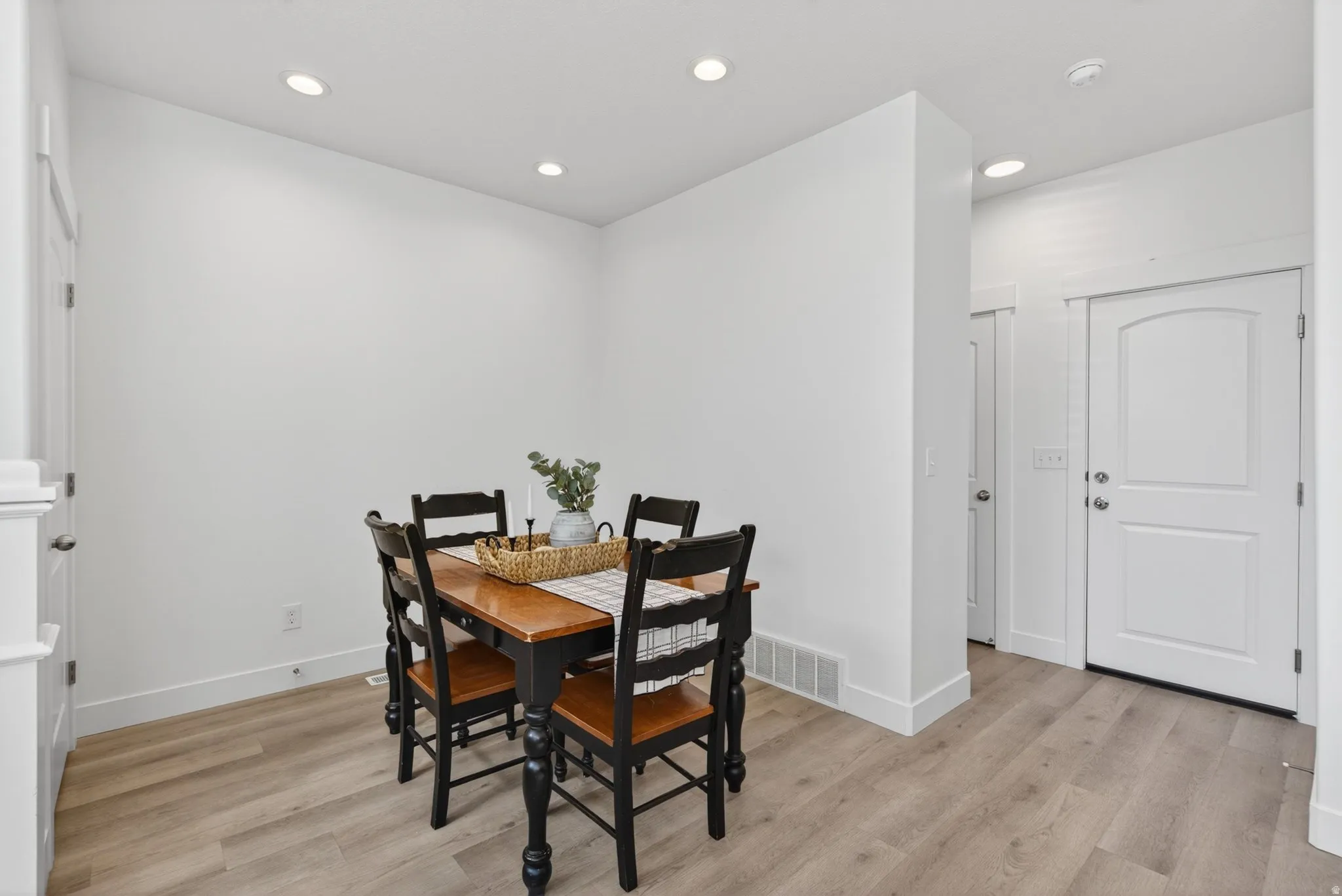 Dining area featuring wood-finish flooring, recessed lighting, and crisp white baseboards