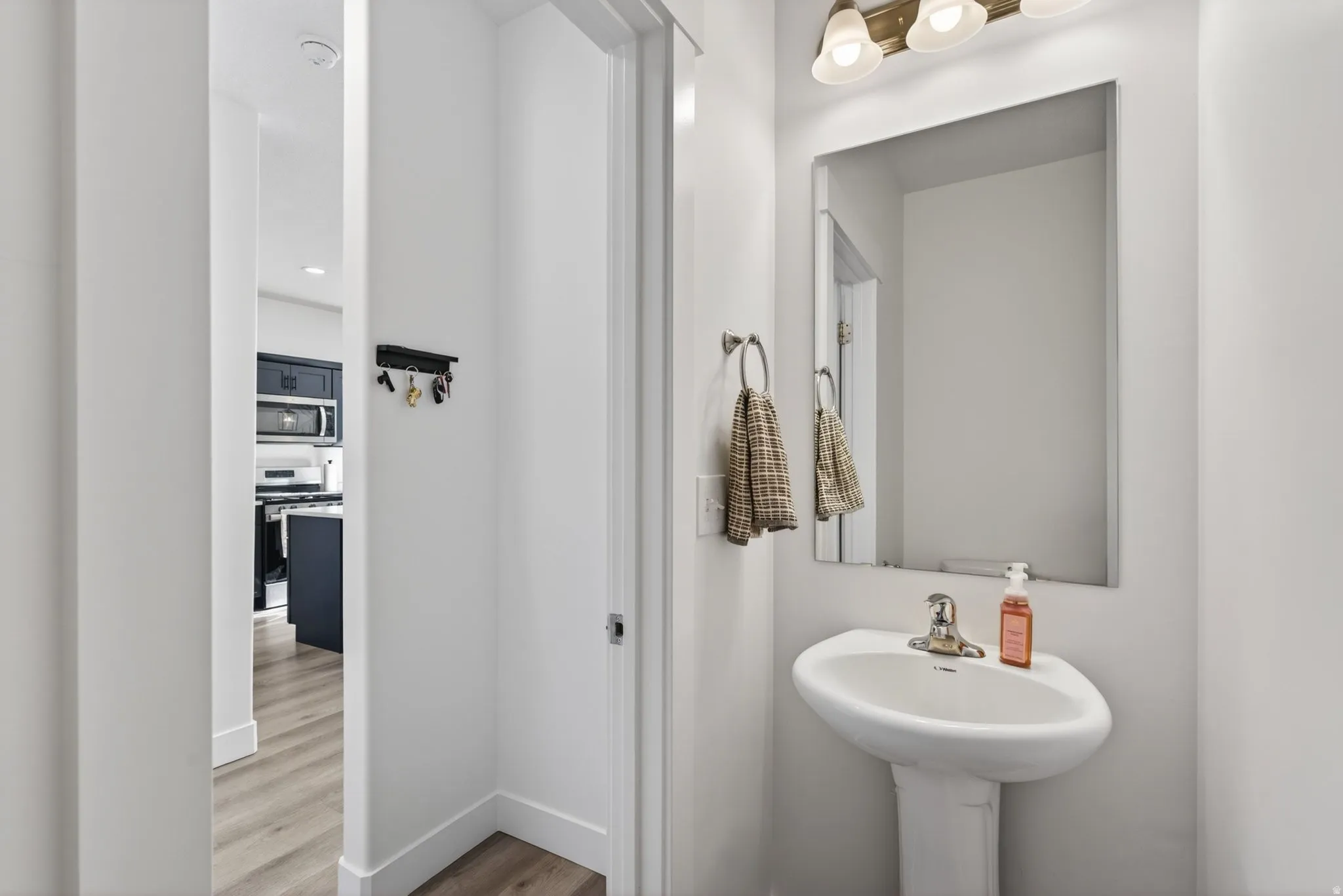 Pedestal sink with a polished chrome faucet and an overhead vanity light fixture