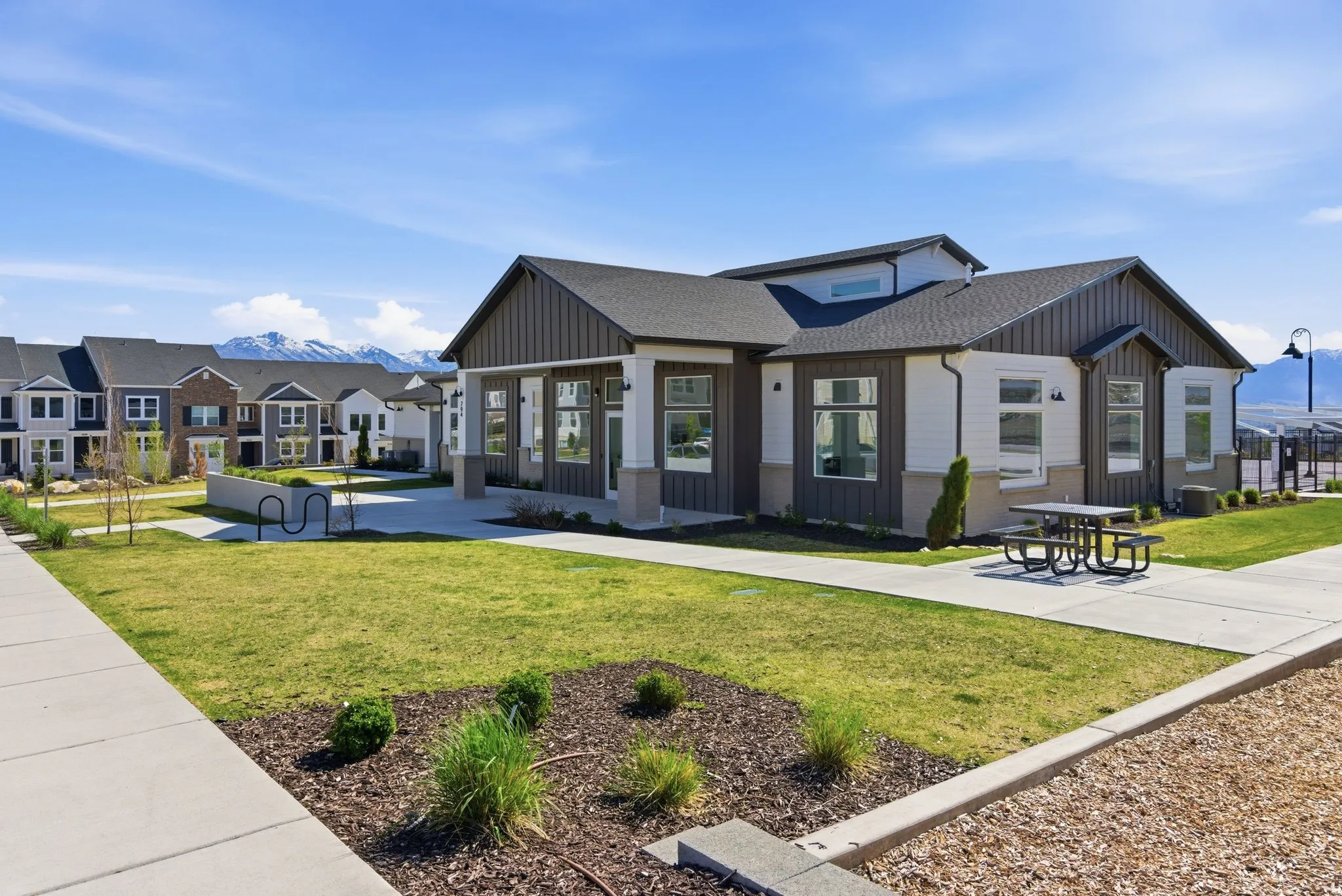 Contemporary building featuring a dark gray roof, white siding, and vertical dark wood-finish accents