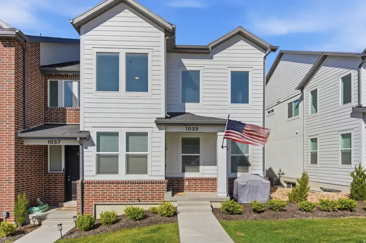 Contemporary townhome exterior featuring white horizontal siding and a red brick base