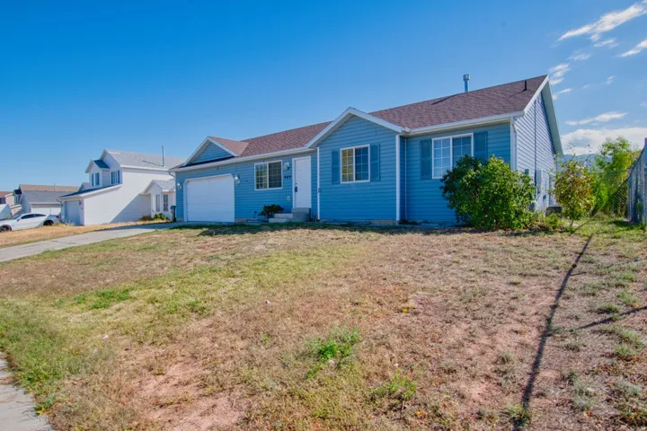 Blue siding exterior with white trim, a brown shingle roof, attached garage, and a chain-link fence