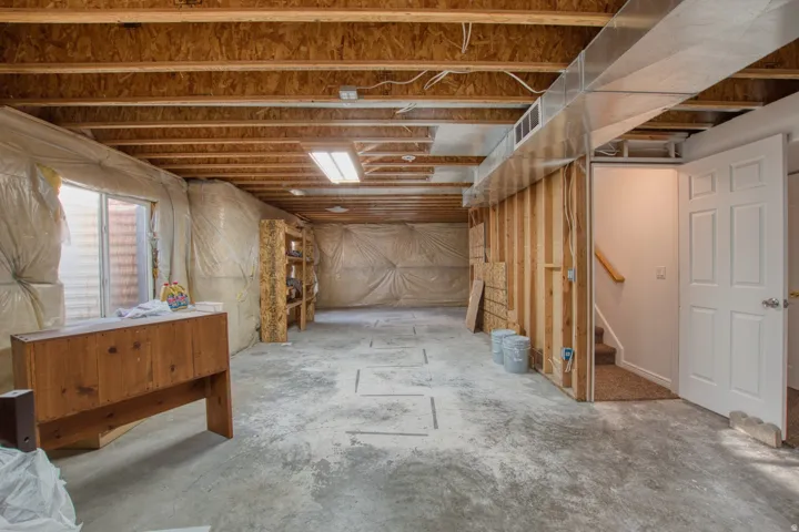 Unfinished basement featuring concrete flooring, exposed wood ceiling joists, and visible insulation