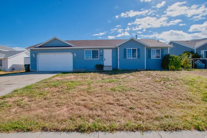 Blue siding exterior with white trim, attached garage, and paved driveway