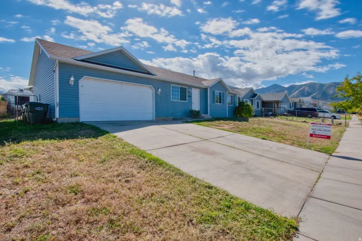 Blue siding with white trim, attached two-car garage, concrete driveway, and a sidewalk