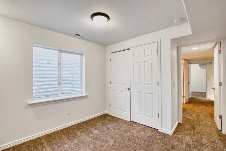 Carpeted room with a white window frame, white walls, and a ceiling-mounted light fixture