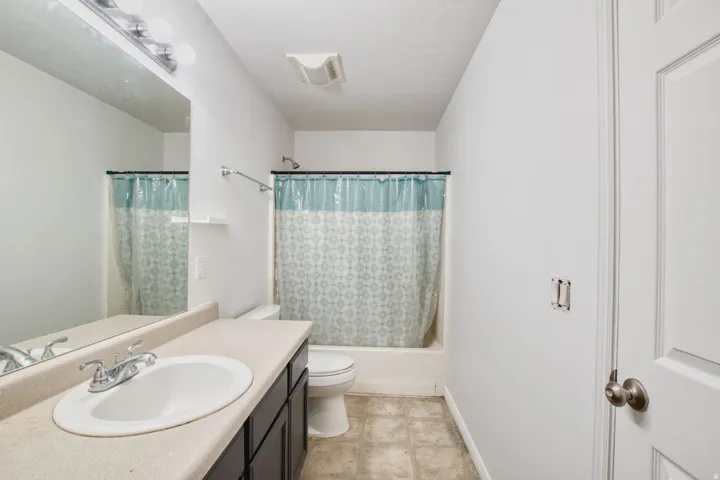 Full bathroom featuring a single vanity with a laminate countertop, built-in cabinetry, and overhead bar lighting