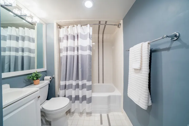 Bathroom featuring a white vanity with integrated sink, toilet, and a bathtub with tiled surround