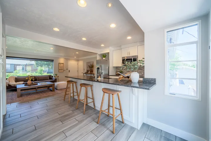 Kitchen island with bar seating, integrated stainless steel sink, and dark stone countertop