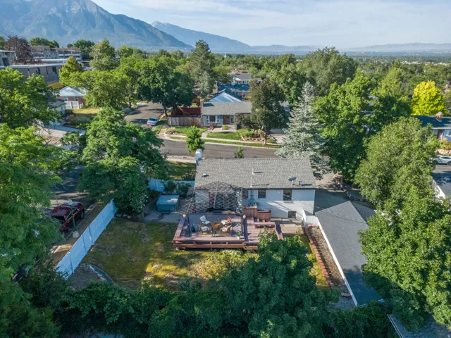 Expansive backyard featuring a multi-level wood deck, a sunken hot tub, and a white privacy fence
