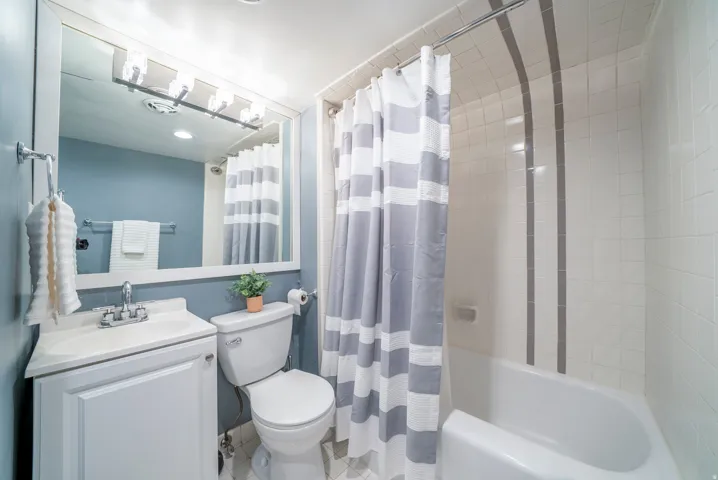 Bathroom featuring a shower-tub combination with tile surround and decorative accent strips