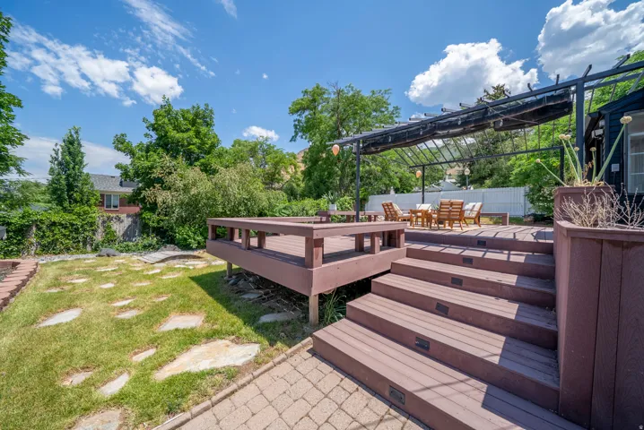 Multi-level outdoor deck featuring integrated steps with lighting, a shaded pergola, and composite decking materials