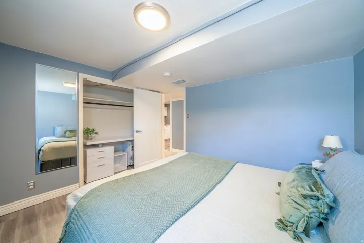 Bedroom featuring wood-finish flooring, a flush-mount ceiling light, and light blue wall tones